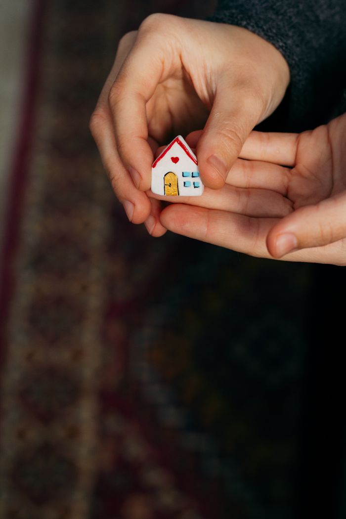 hero-img-01 Close-up view of hands gently holding a small house model, symbolizing home and security.