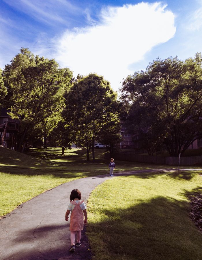 hero-img-02 Two children walk on a sunlit path in a peaceful summer day.