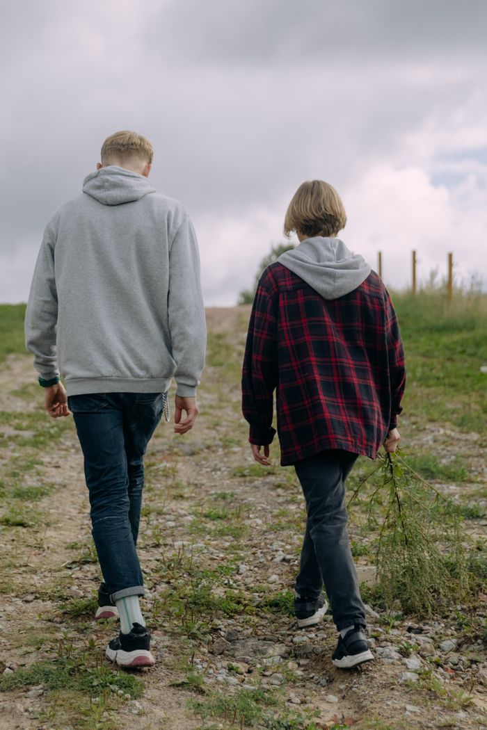 contact-img Two individuals walking on a gravel path outdoors, enjoying a peaceful day.